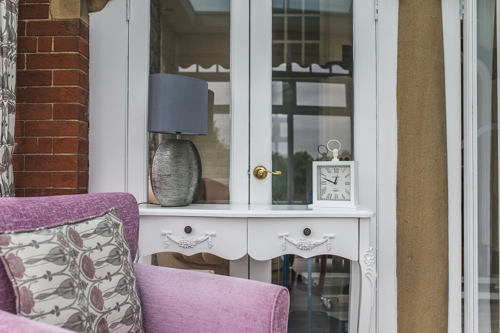 Close up view of living room with white glass paned doors, lamp and purple armchair
