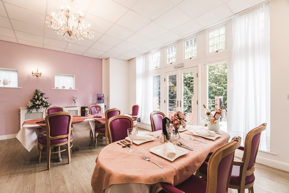 Dining area decorated with pink accents and purple chairs featuring large windows and soft lighting