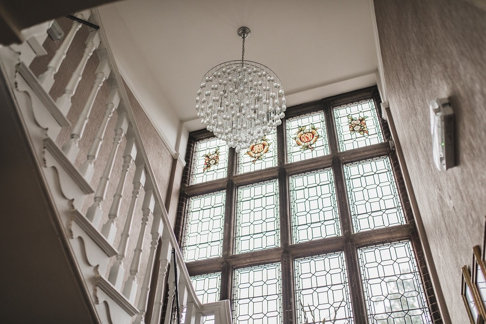 Elegant interior view of a stairwell with large decorative stained glass windows and a modern chandelier